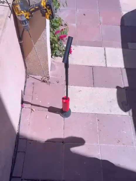 גשש של מכשיר איתור גז מונח על ריצוף החצר, צמוד לקיר