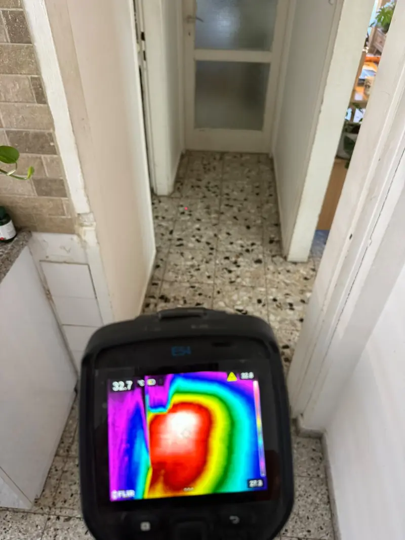 מסך מצלמה תרמית מעל רצפת טראצו: כתם חם בצבעי אדום ולבן מסמן נזילה בצנרת המים החמים